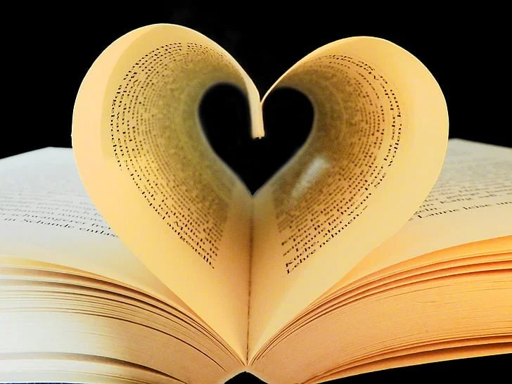 An open book with pages shaped into a heart